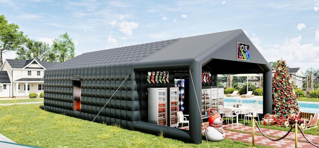 Black inflatable nightclub tent set up outdoors with a pool in the background. The structure has large windows on the side, tables and chairs arranged outside, and features a colorful logo above the entrance.