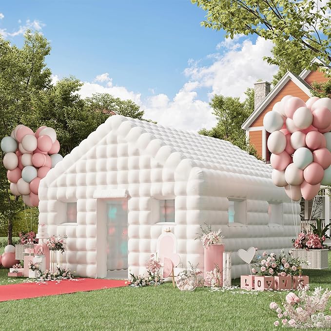 A white inflatable nightclub tent set up outdoors with pink and pastel-colored balloons, floral arrangements, and a red carpet leading to the entrance. The surrounding area is decorated with love-themed accents, creating a festive and romantic atmosphere.